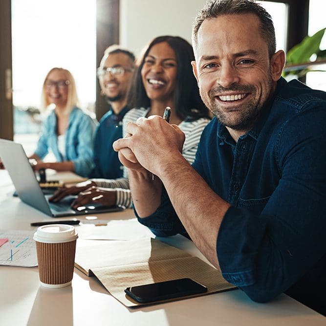 Smiling mature businessman sitting with colleagues in an office