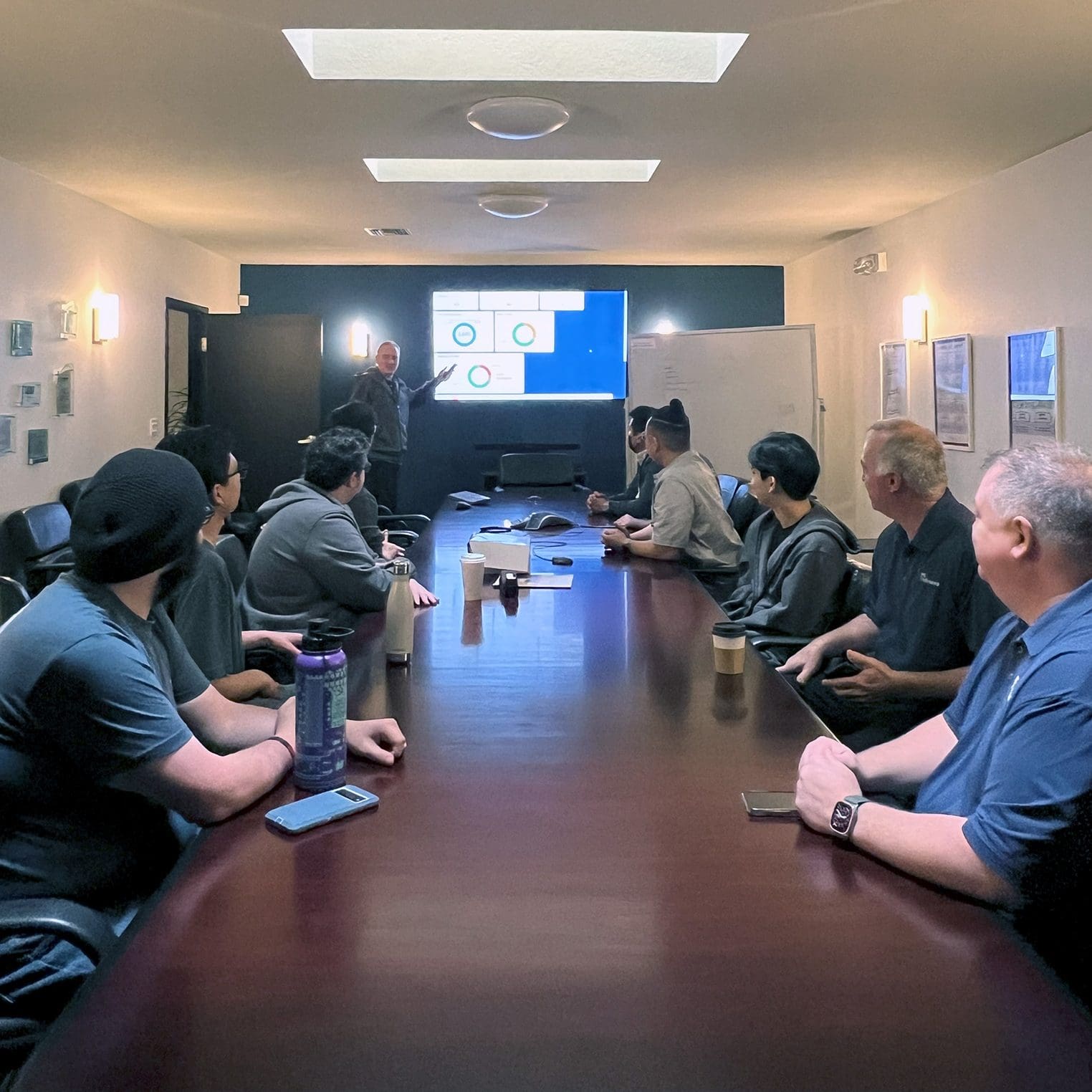 Group of IT professionals seated around a conference table viewing a presentation on outsourcing IT services.
