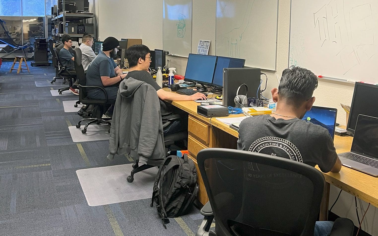 PC Professional technicians seated in a row at desks, each working on a desktop computer