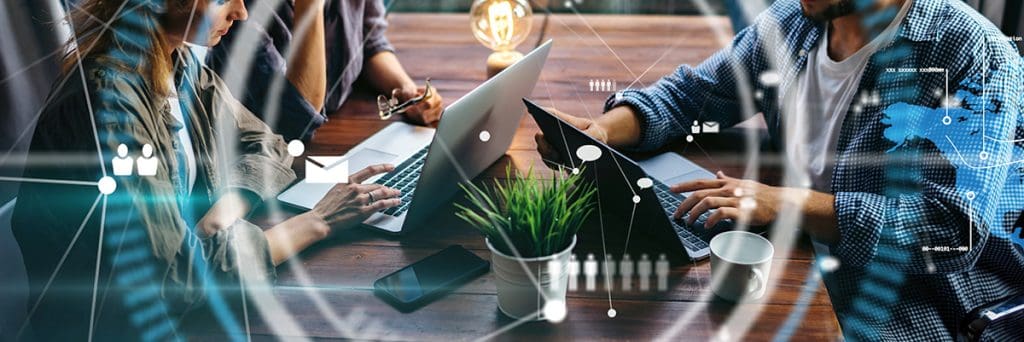 Two professionals at a wooden table working on laptops, overlaid with digital network and cloud computing icons